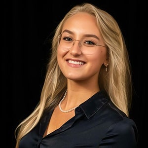 Portrait of woman with blonde hair, glasses, black long sleeve shirt