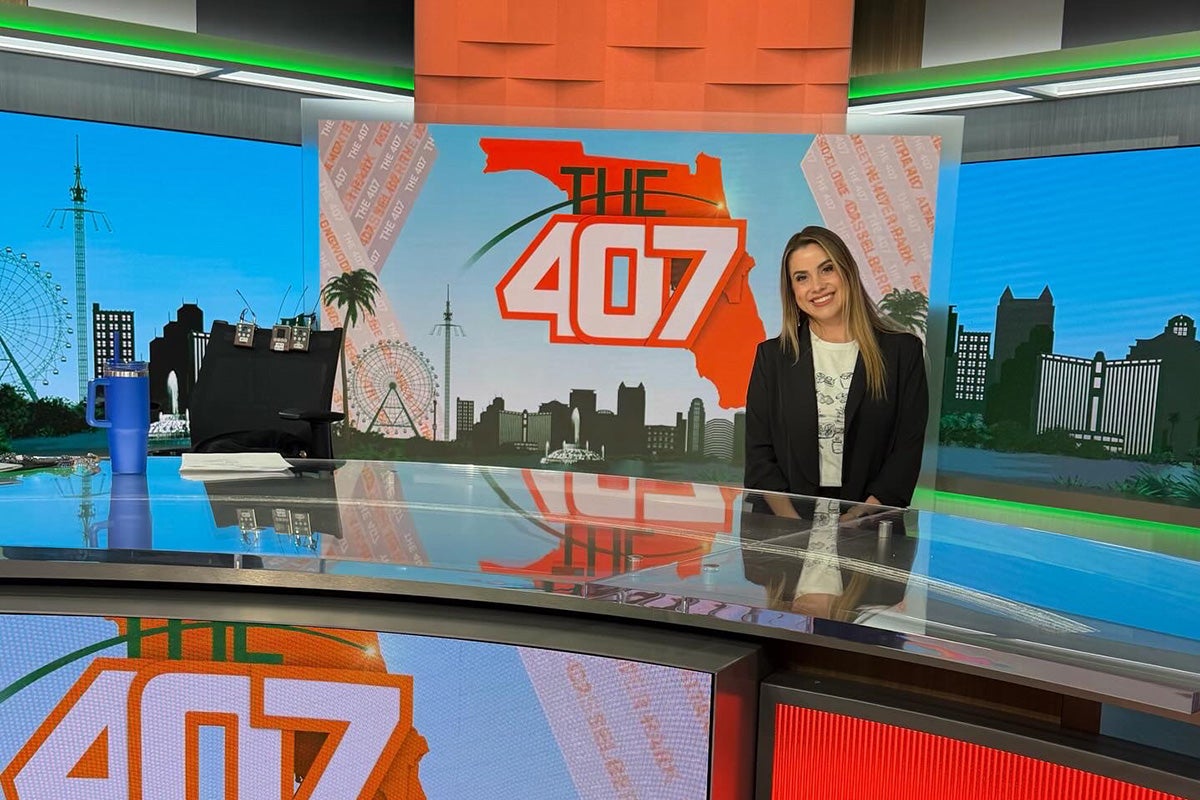Woman in black blazer sits on news studio set with color "The 407" graphic overlayed on outline of state of Florida