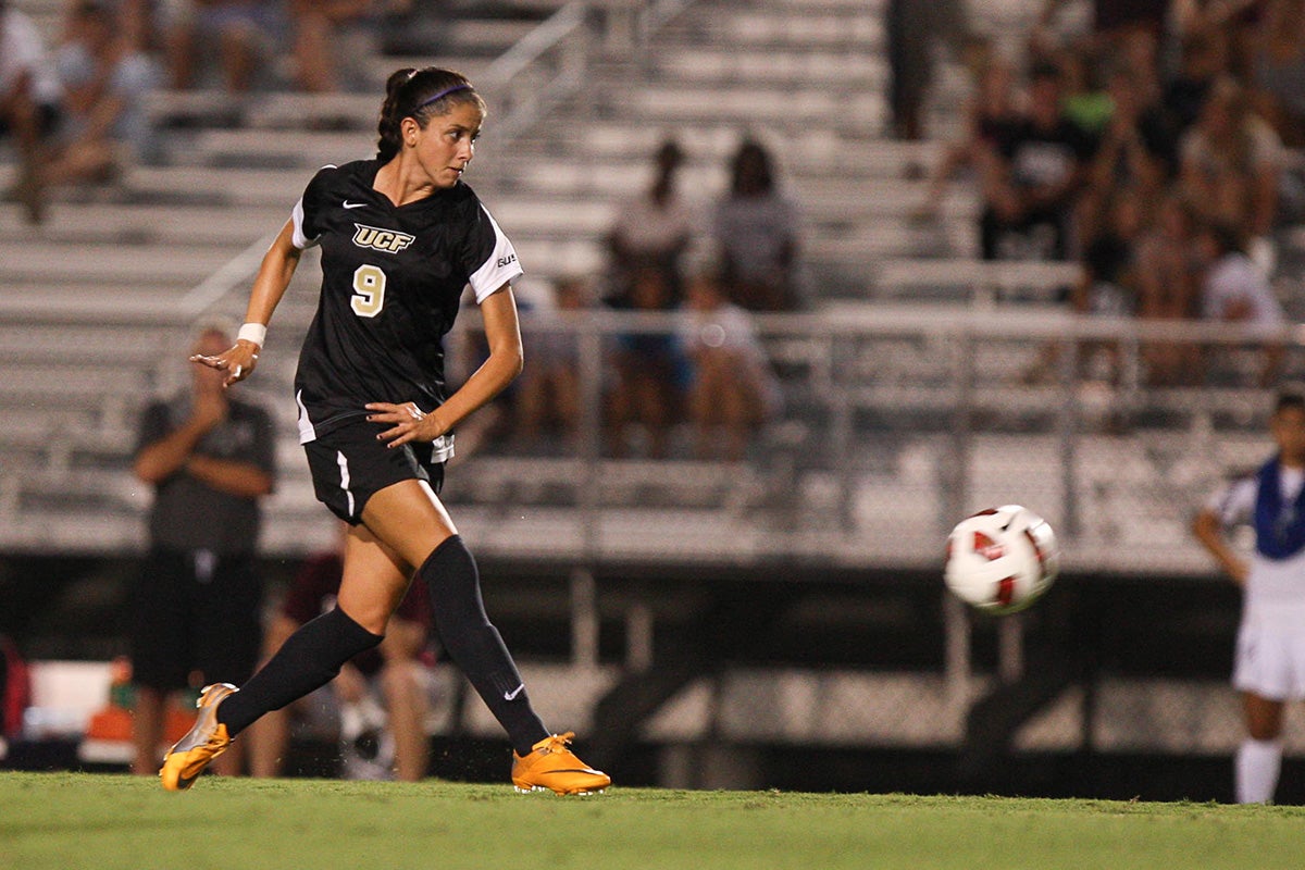 Brunette woman wearing black #9 UCF soccer uniform kicks soccer ball on field