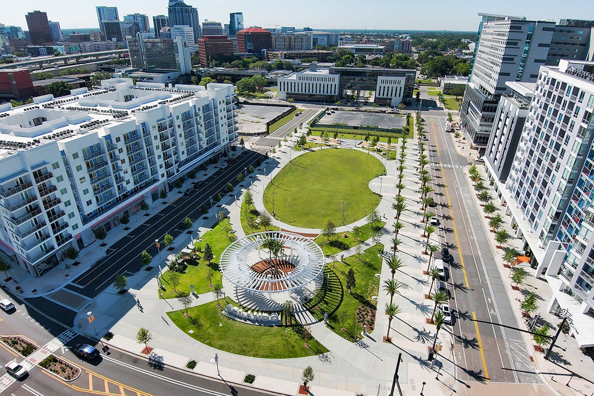 aerial shot of green space with buildings around its perimeter and skyline in background
