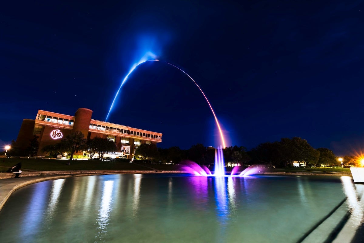 Blue and purple streak in the night sky over UCF's John C. Hitt Library