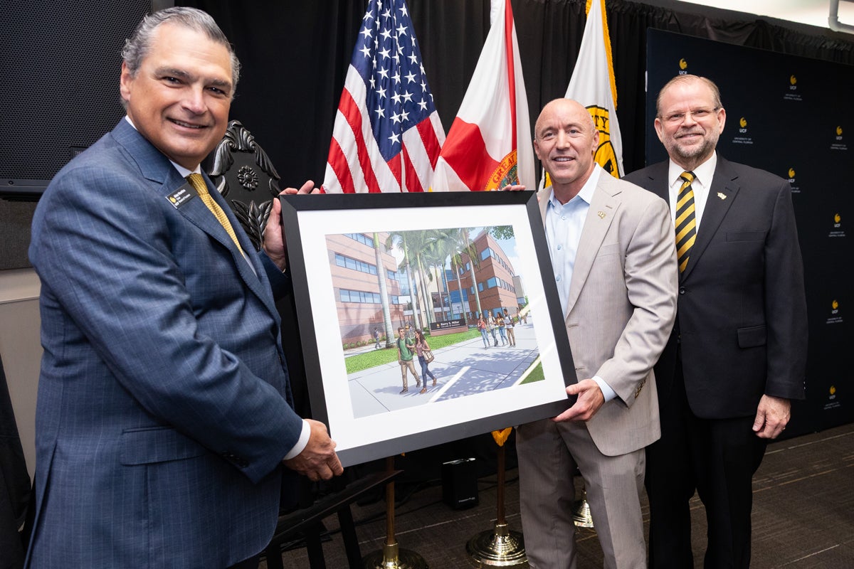 Three people holding a framed rendering