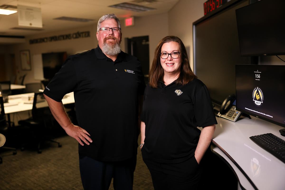 Two people posing for a photo in an emergency operation center