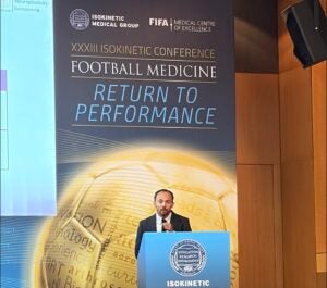 UCF and Orlando Health Sports Physical Therapy program resident Alvaro-Zapata speaks at a podium in front of a large screen and signage reading “Isokinetic Conference: Return to Performance.”