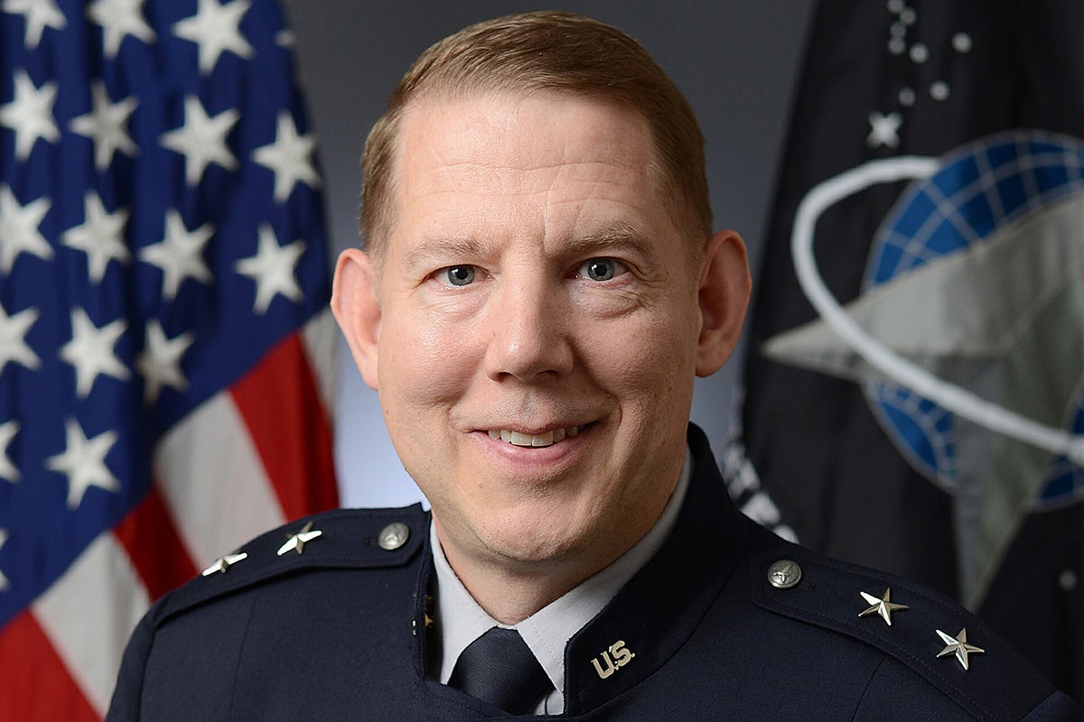 Portrait of man in military dress uniform and tie in front of USA flag and Space Force flag