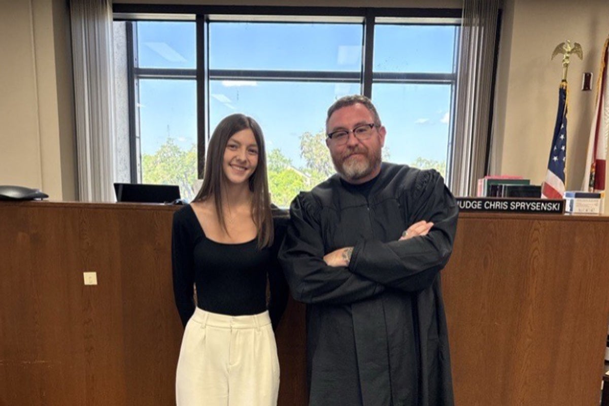 Judge Christopher Sprysenski, a UCF adjunct instructor, stands next to a student in a courtroom.
