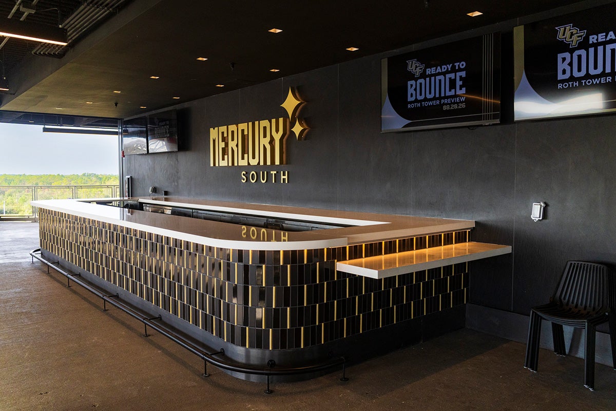 Outdoor bar space with black and gold theme and a sign that reads Mercury South on the wall with TVs flanking it