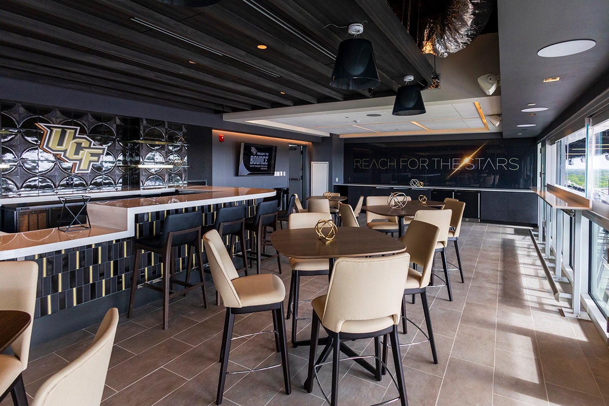 Empty bar space with beige, gold and black color scheme and a wall that reads "Reach for the Stars" with a starburst