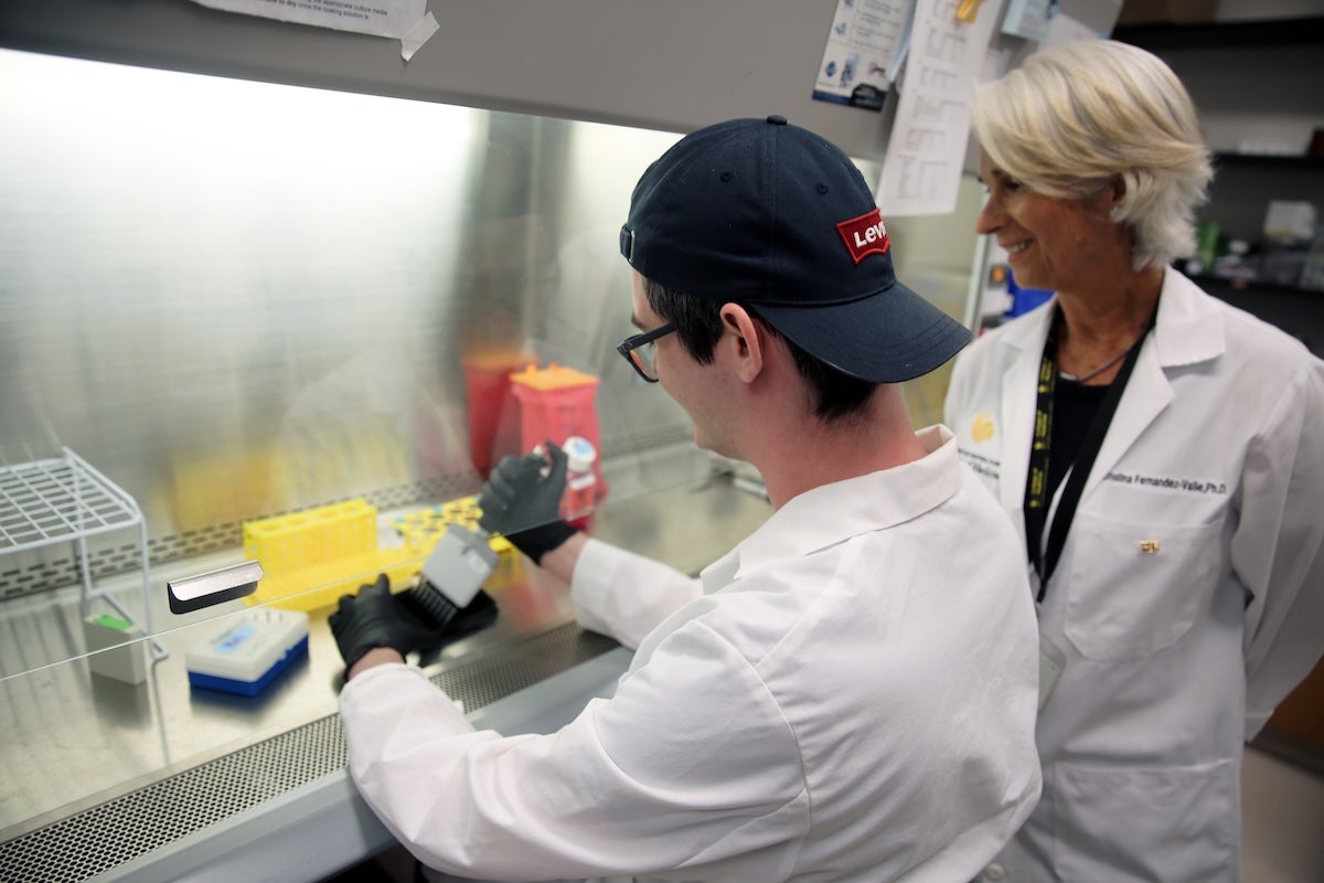 A UCF student uses a pipette while UCF Professor Cristina Fernández-Valle observes him in a research lab.