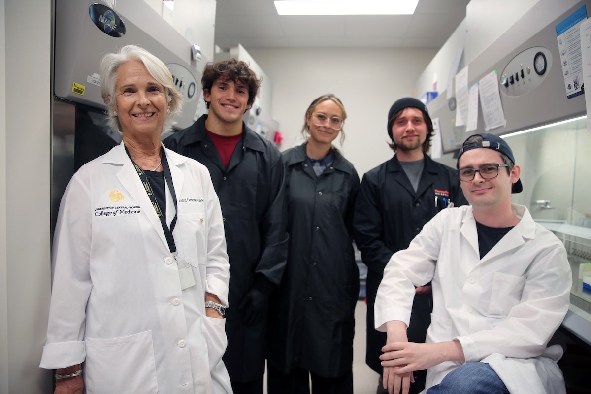 UCF Professor Cristina Fernández-Valle poses with four student researchers in a lab.