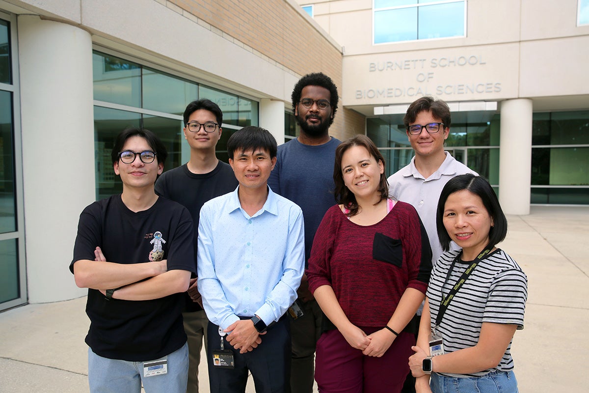 Dr. Nguyen stands in center, surrounded by six of his students in courtyard of College of Medicine