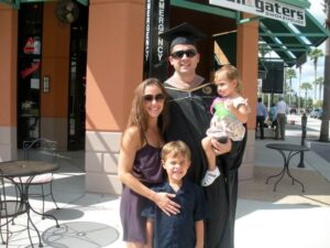 A person wearing a graduation cap and gown and posting for a photo with family members