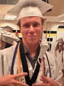 Portrait of Blonde male in white graduation cap and gown