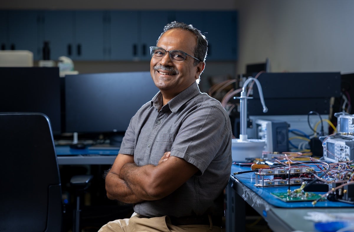 Anish Damodaran sits cross armed on a chair in a laboratory.