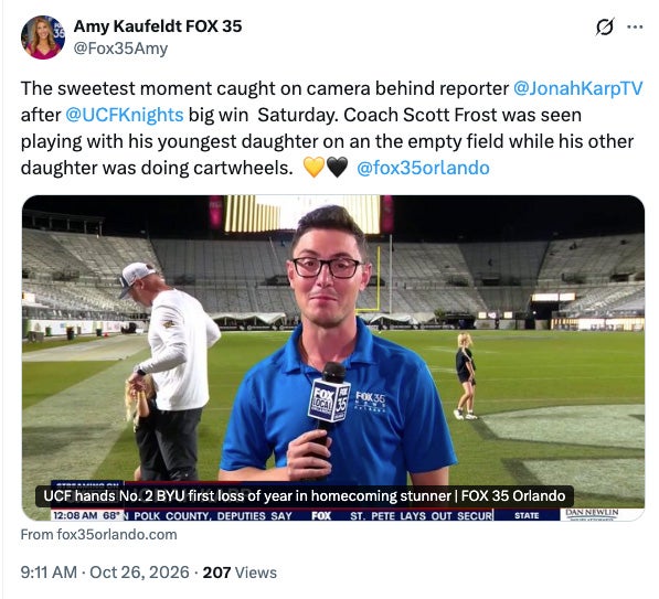 X post by Amy Kaufeldt: The sweetest moment caught on camera behind reporter @JonahKarpTV after @UCFKnights big win Saturday. Coach Scott Frost was seen playing with his youngest daughter on an the empty field while his other daughter was doing cartwheels.