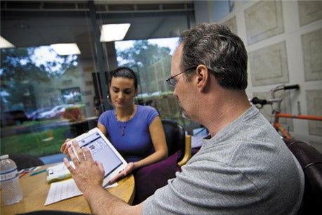 Photo of a client communicating with a student using an iPad application in the Aphasia House den
