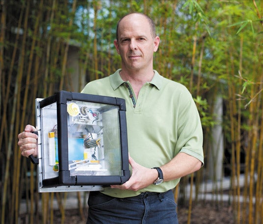 Photo of Dr. Joshua Colwell holding an impact chamber.