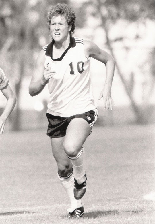Photo of Michelle Akers running in a field.