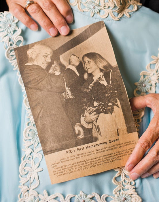 A newspaper clipping about the crowning of the first Homecoming Queen, held in front of Patty Gray Neff's dress.