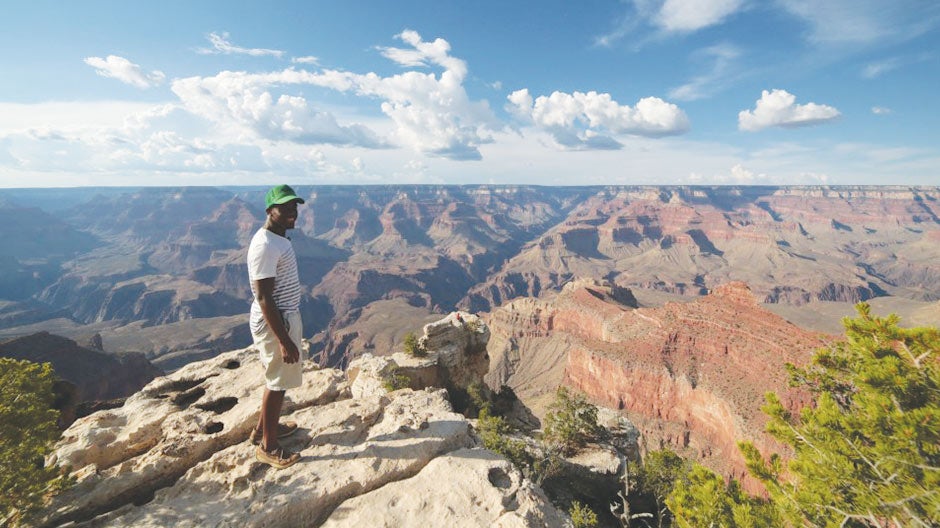 A person standing next to a cliff at the Grand Canyon