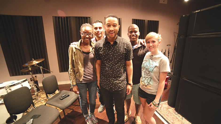 Four people posing with John Legend