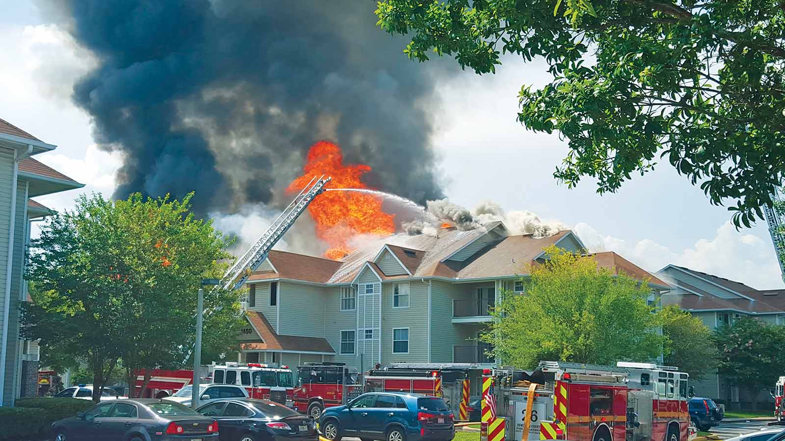 Orlando firefighters spraying rooftop fire at Tivoli Apartments in Orlando, Florida