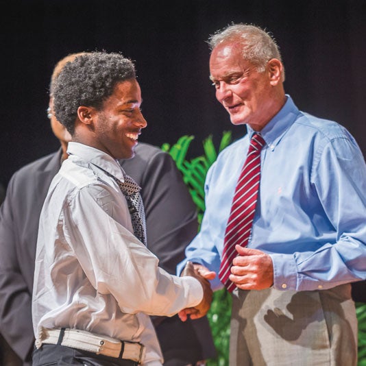 Harris Rosen shaking boy's hand on stage