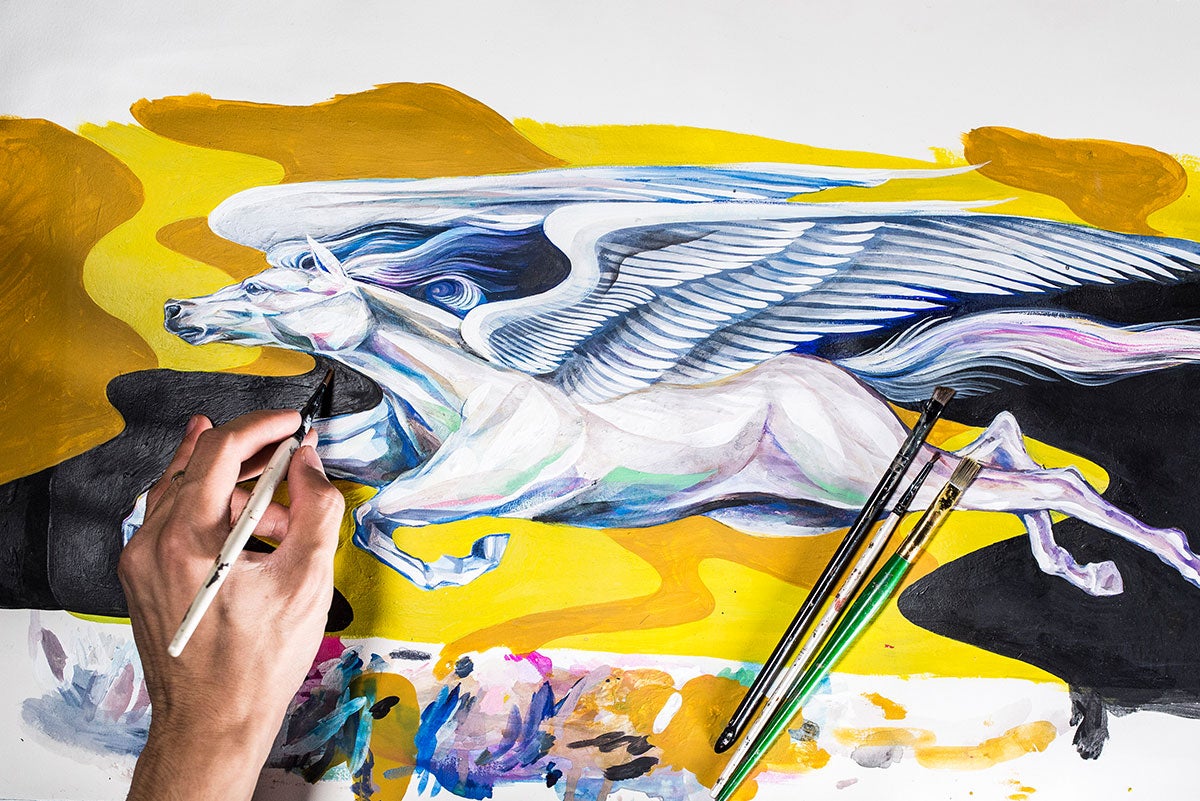 An image of the painting from above shows Boy Kong's hand painting a white, winged horse in flight with a yellow and black background. Paint brushes lay on top of the painting.