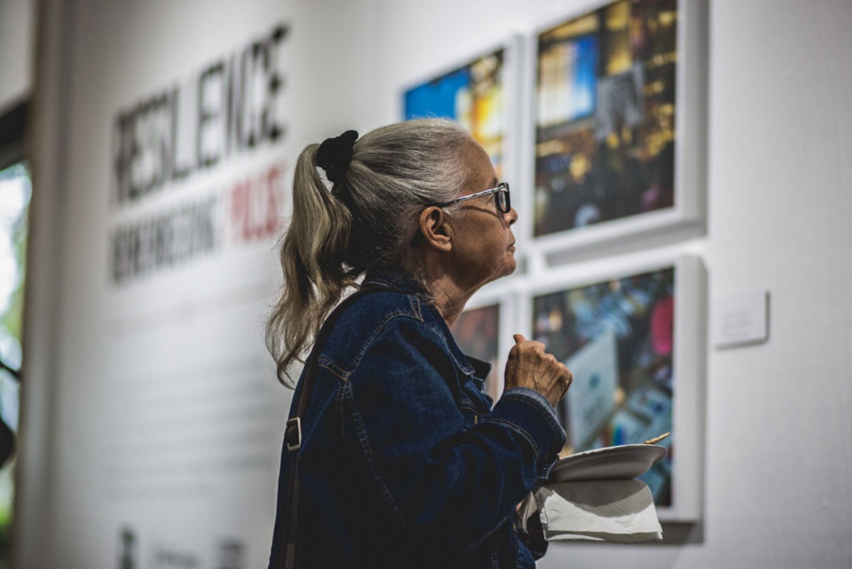 An older hispanic-looking woman looks at artwork in a gallery.