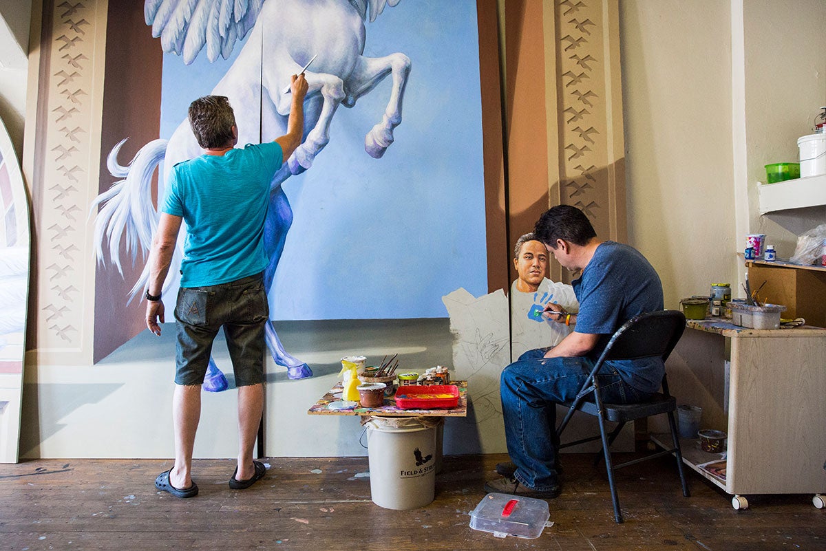 Yuriy Karabash, standing, and Michael Pilato, sitting, are painting part of a mural.
