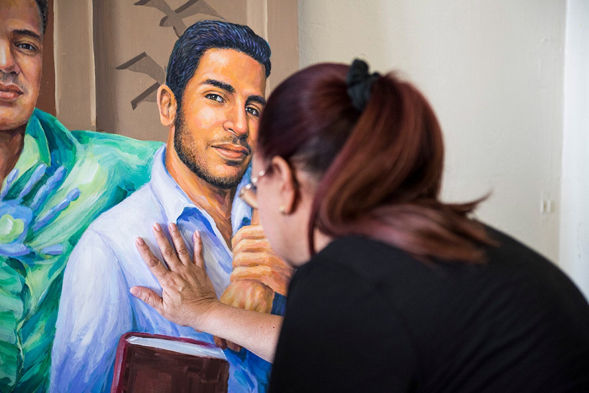 Mayra Guerrero presses her hand against a painting her son.