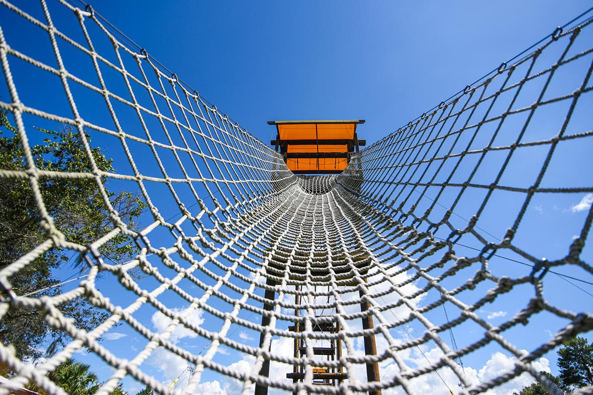 An empty rope net stretches to the base of a wooden platform. An empty rope net stretches to the base of a wooden platform.