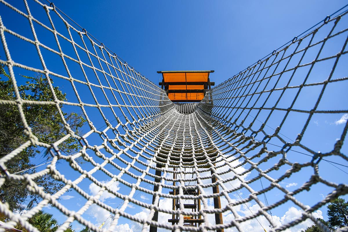 An empty rope net stretches to the base of a wooden platform.