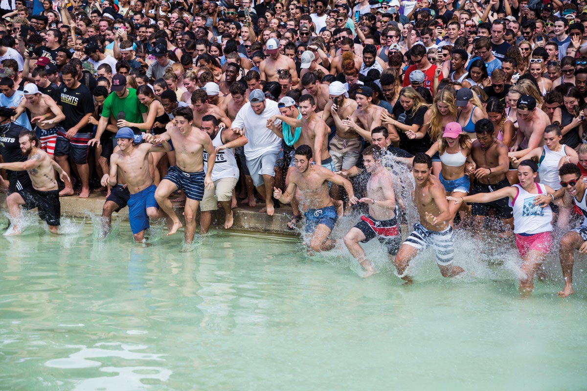 A group of students rush into the water of the Reflecting Pond.