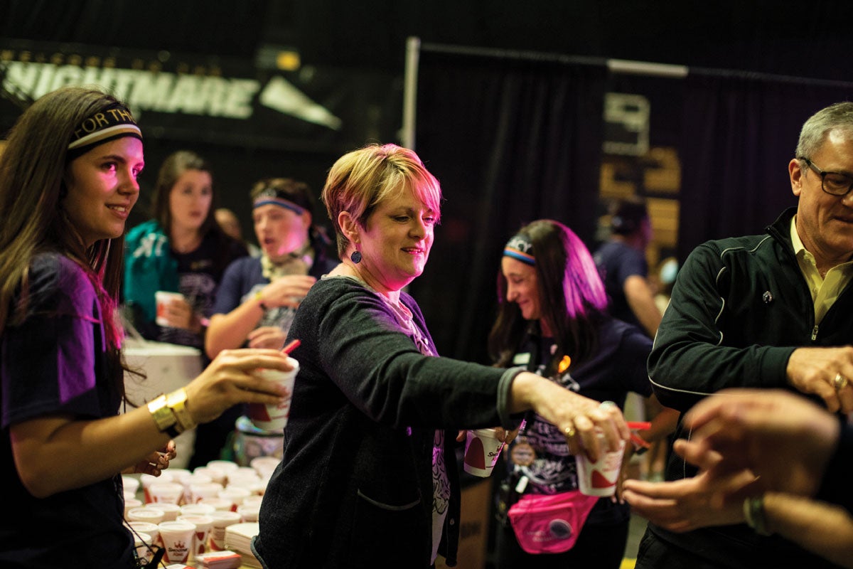 Mary Whittaker smiles as she hands a smoothie to a student.