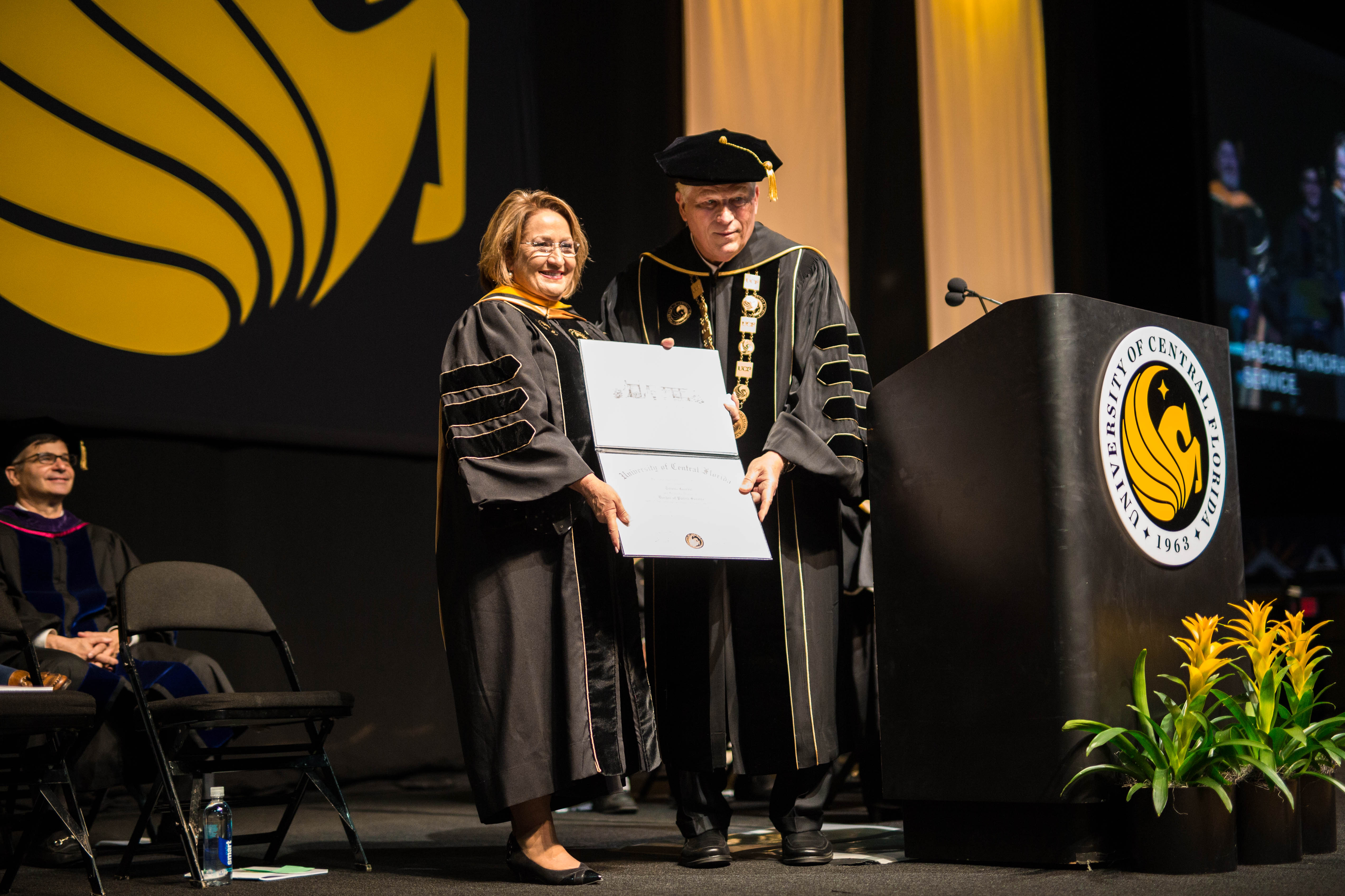 Orange County Mayor Teresa Jacobs holds a honorary diploma as John C. Hitt presents it to her own stage.