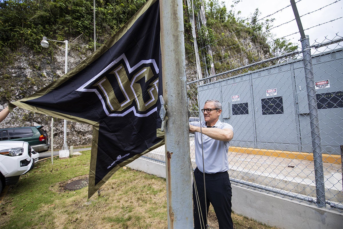 President Dale Whittaker putting up ucf flag at Arecibo.