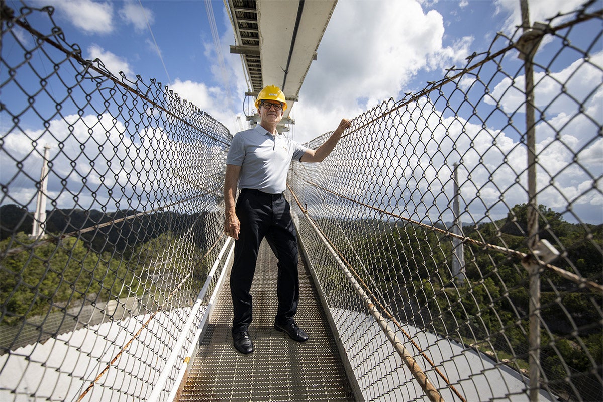 President Dale Whittaker standing on a suspension bridge over Arecibo.