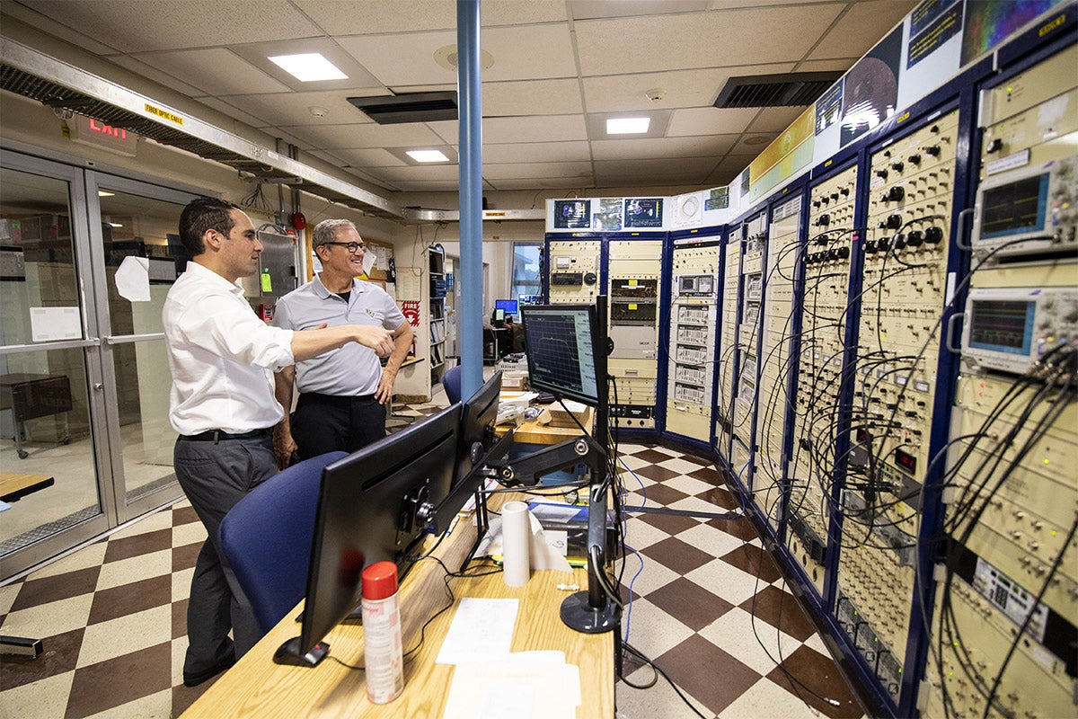 UCF President Dale Whittaker stands in computer room with man talking and admiring the Arecibo facility.