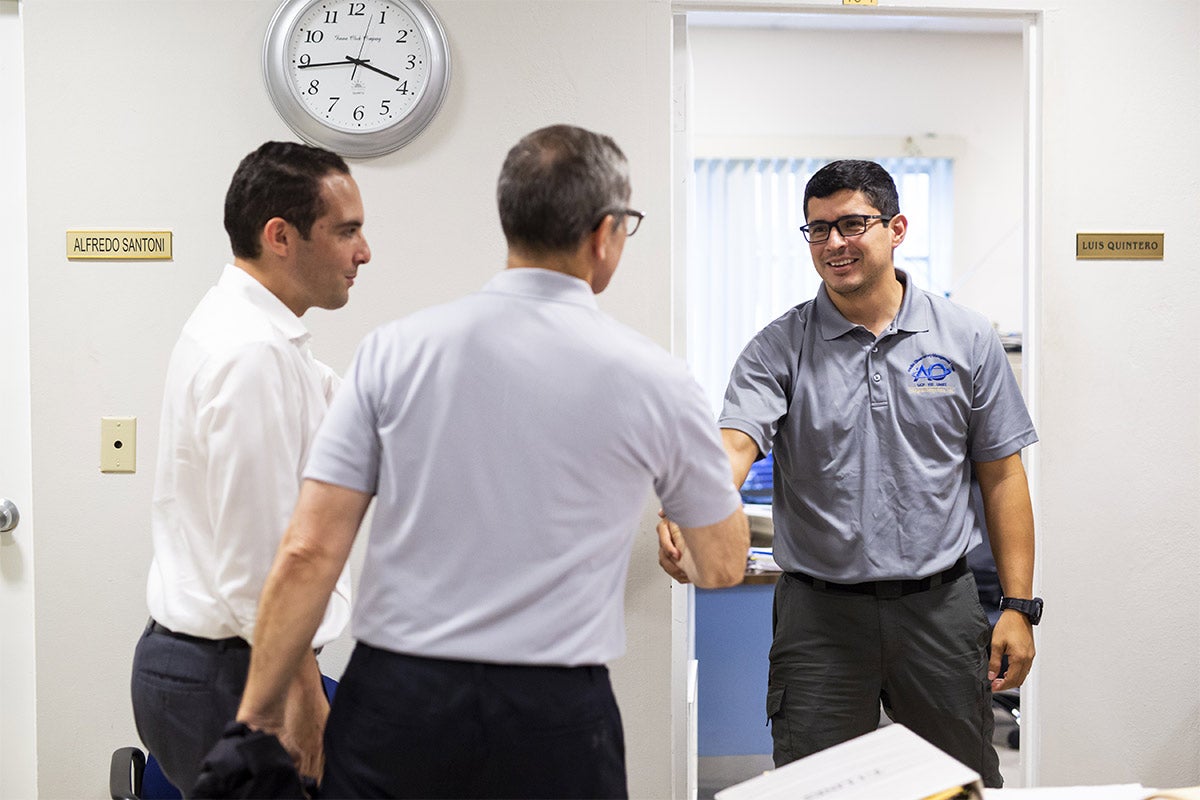 President Dale Whittaker shaking hands with Luis Quintero in office.