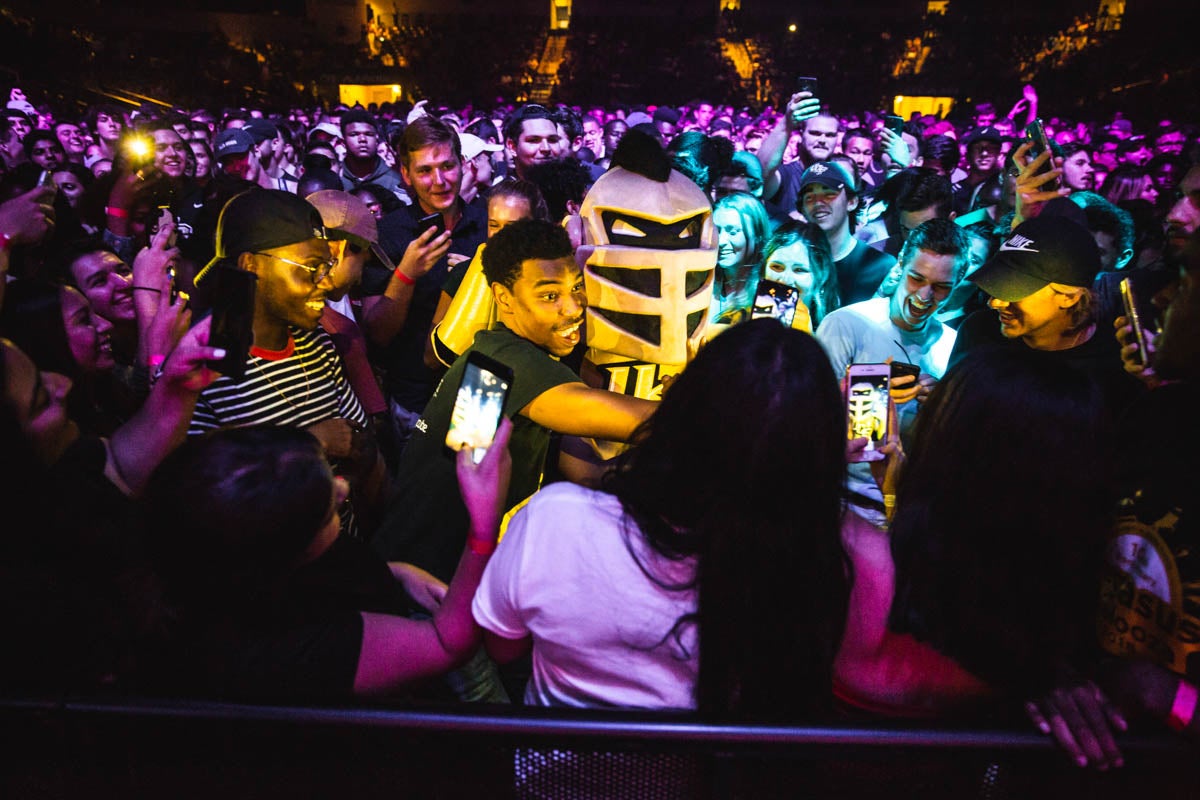 A guy hugs someone in a knight costume as a crowd forms around them.