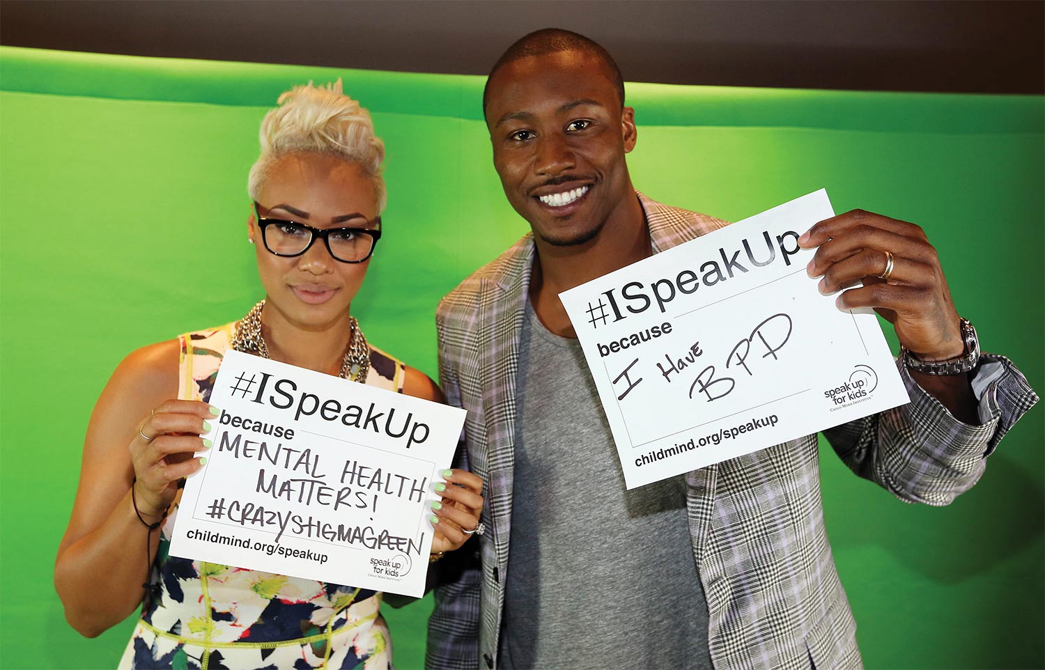 A man and a woman hold up signs against a green background.
