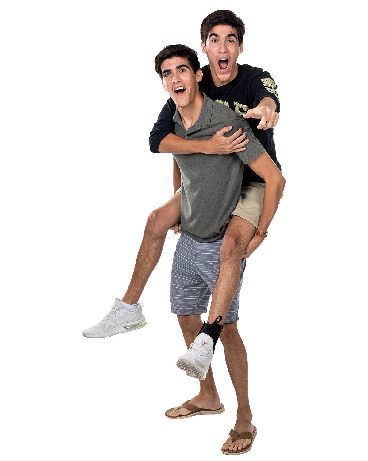 A man holds his twin who is pointing at the camera on his back. A man holds his twin who is pointing at the camera on his back.