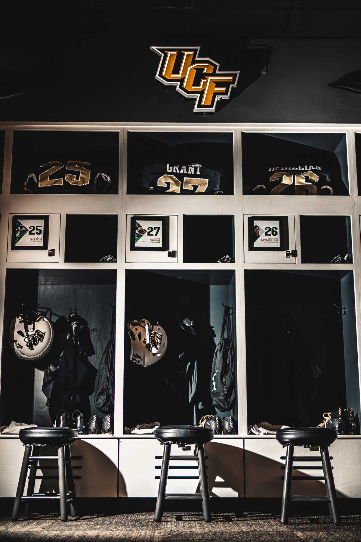 Row of three lockers with white football helmets and black jerseys