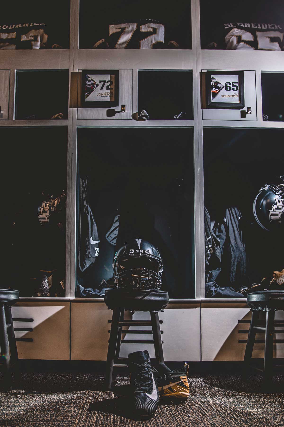 Row of three lockers with black football helmets and jerseys