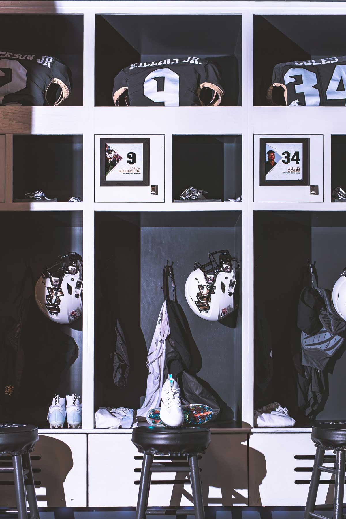 Row of three lockers with white football helmets and black jerseys