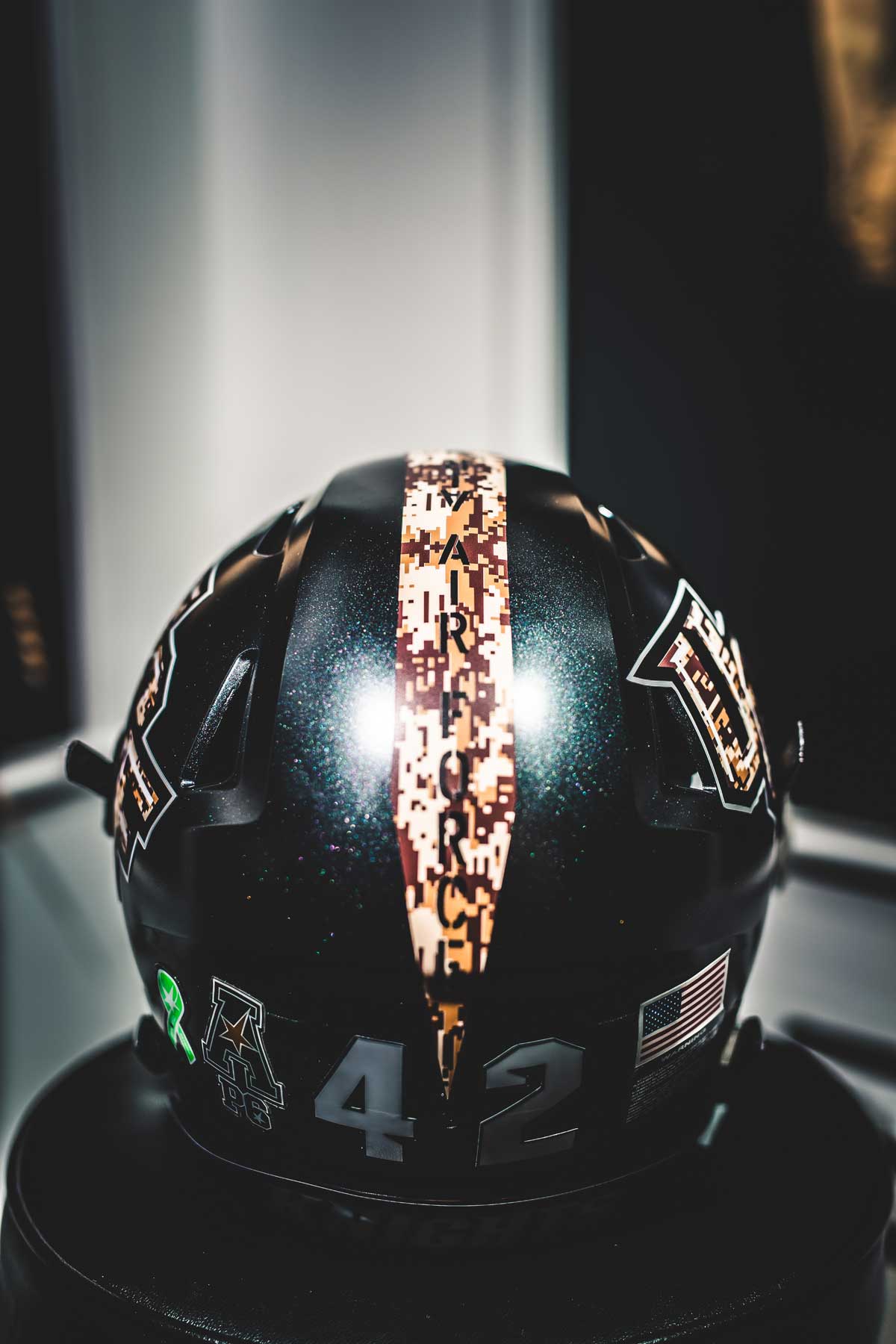 closeup of black football helmet with camouflage stripe down the middle