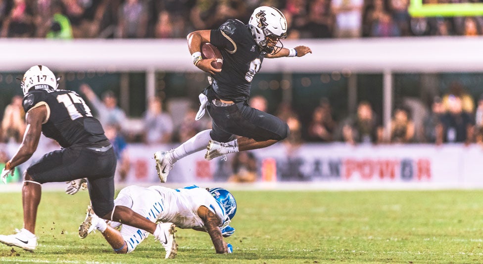 ucf quarterback Darriel Mack Jr. leaps over a memphis player ucf quarterback Darriel Mack Jr. leaps over a memphis player