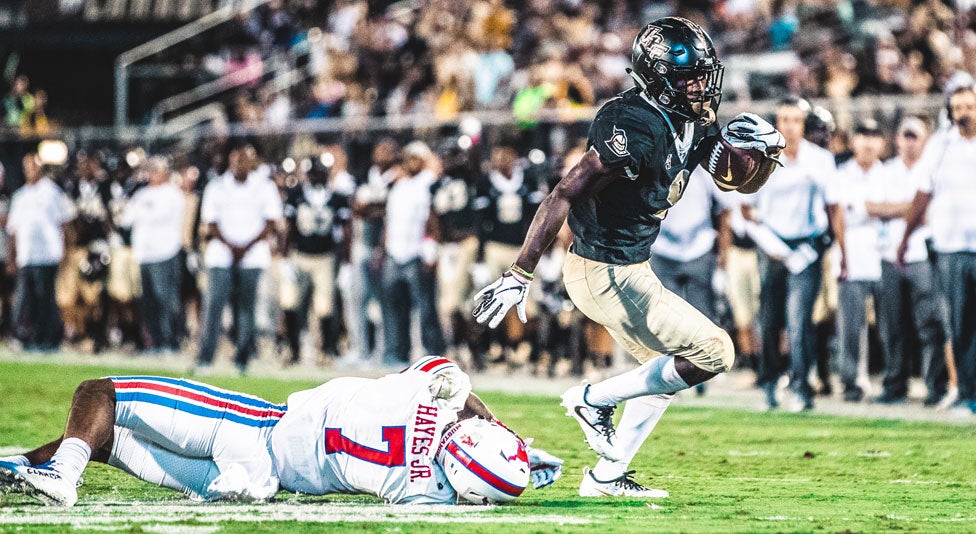 ucf running back Adrian Killins Jr. avoids a tackle from smu football player