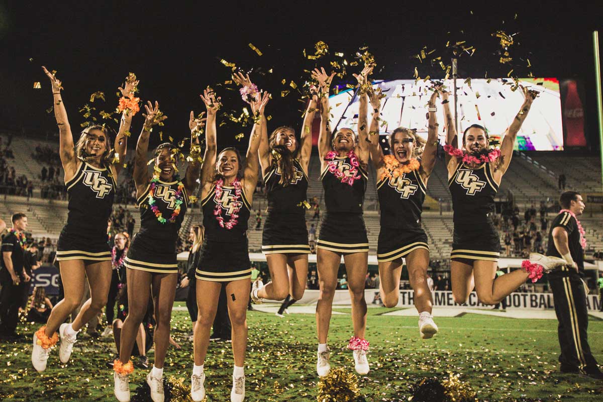 Group of cheerleaders throw confetti while jumping